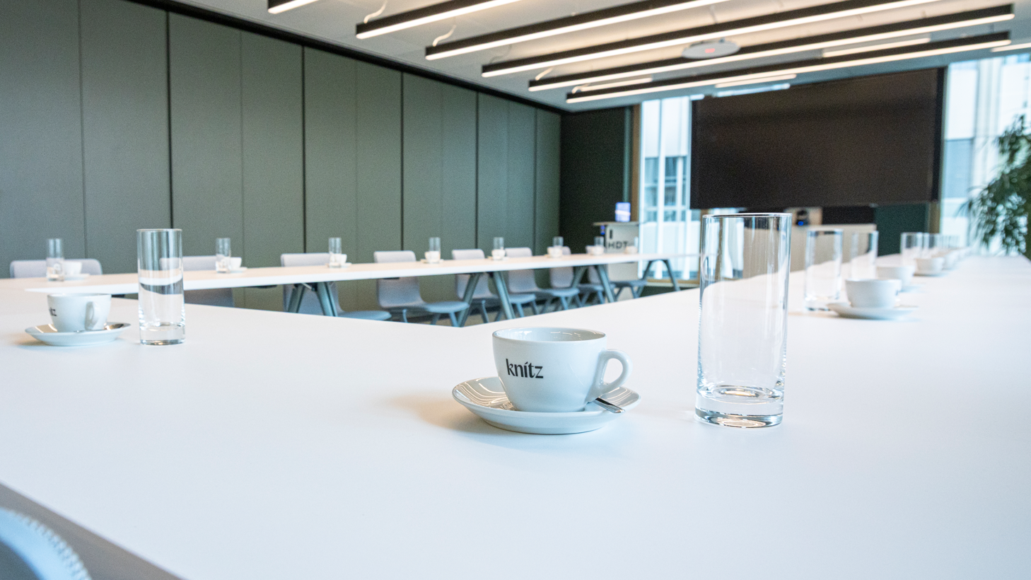 Raum Erlebnis mit Kaffeetassen, Stuttgart-Marketing GmbH, Sarah Schmid Weiße Tische in U-Form, auf den Tischen Tassen mit Logo der In-house-Gastro sowie Wassergläser.