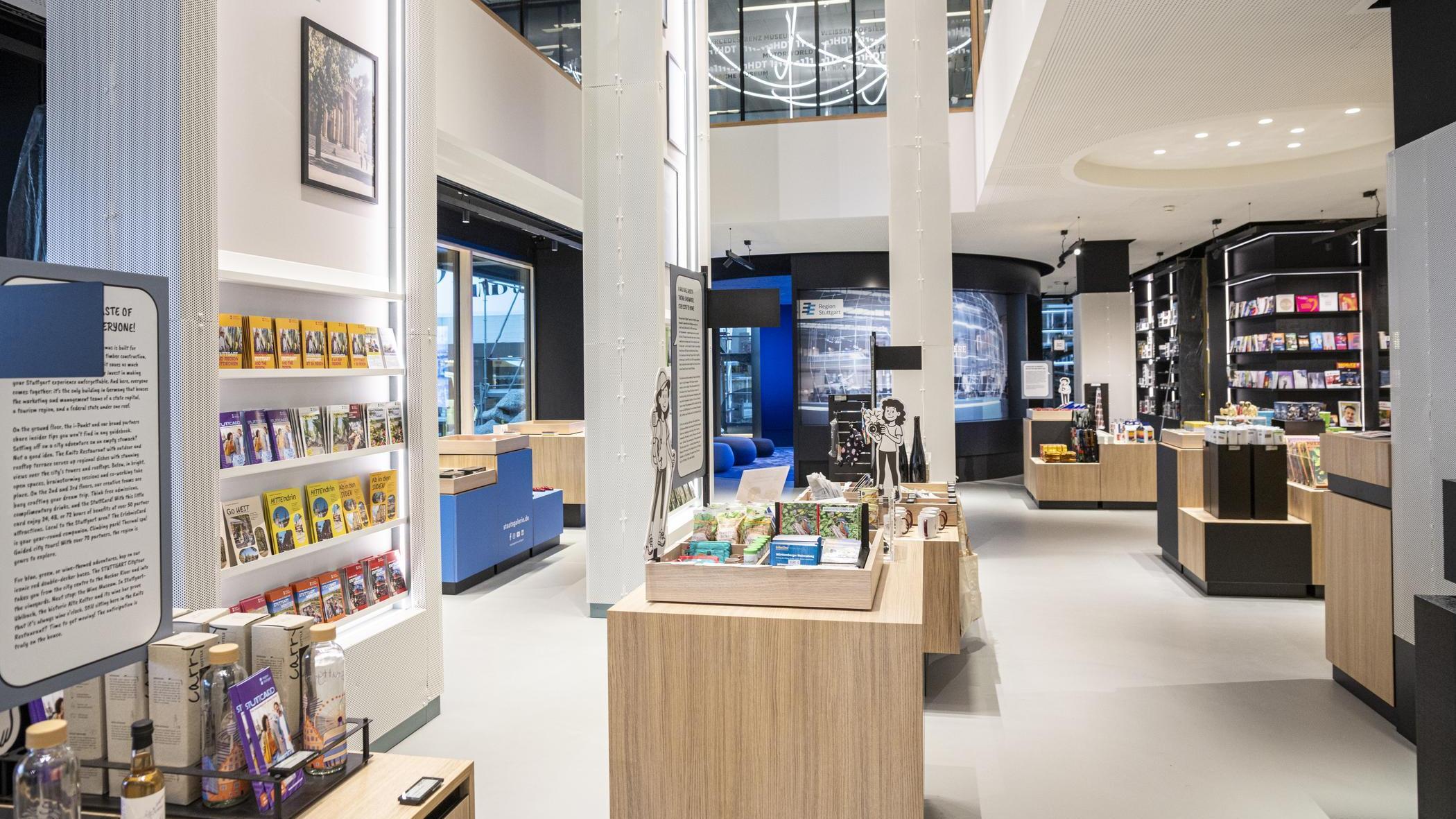 Helle, moderne Tourist-Information Stuttgart mit Regalen und Tischen, auf denen Souvenirs, Bücher und regionale Produkte präsentiert werden.