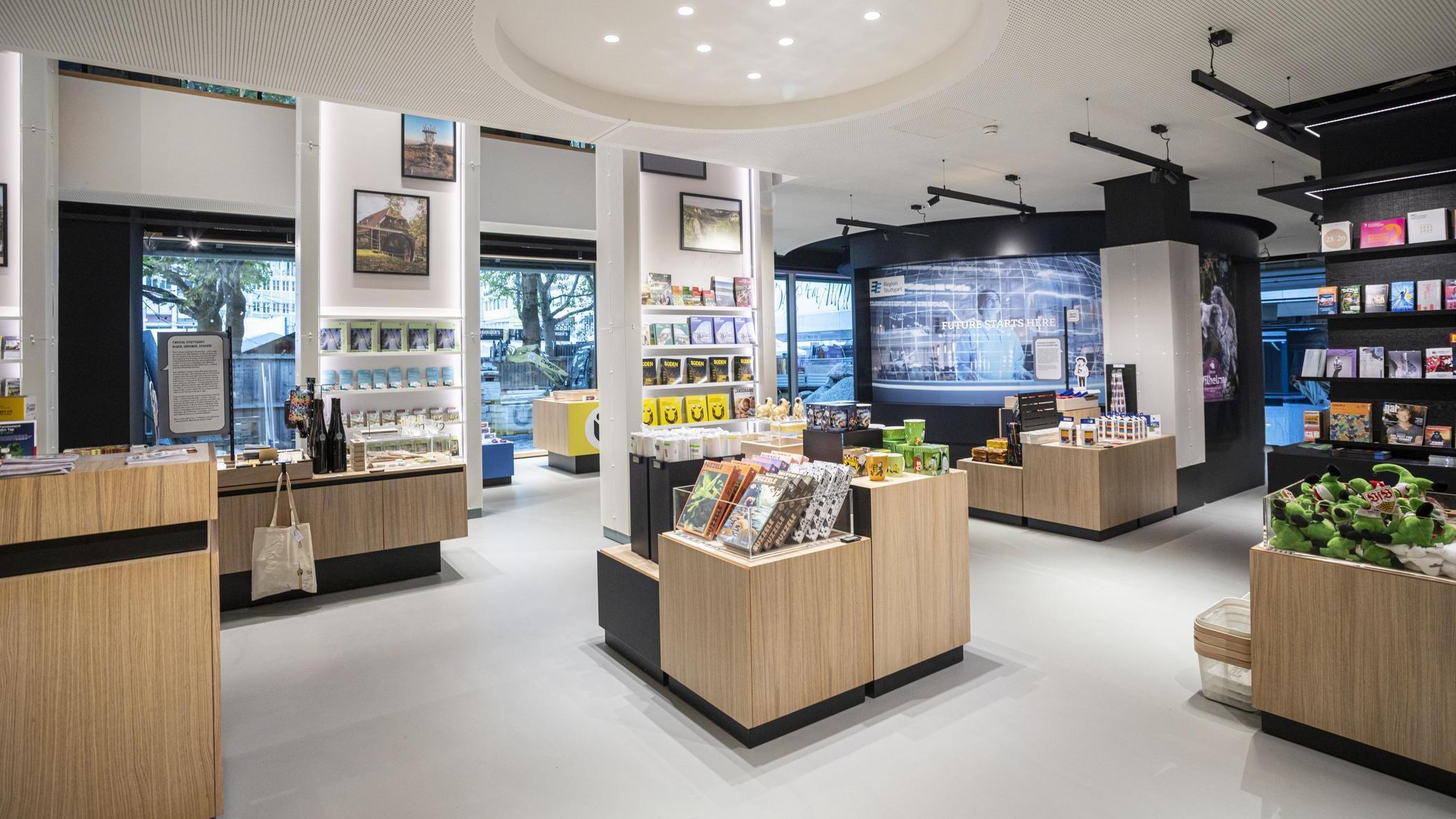 Helle, moderne Tourist-Information Stuttgart mit Regalen und Tischen, auf denen Souvenirs, Bücher und regionale Produkte präsentiert werden.